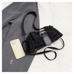 Détail du sac bandoulière noir mat avec boucle argentée et rivets sur blazer gris