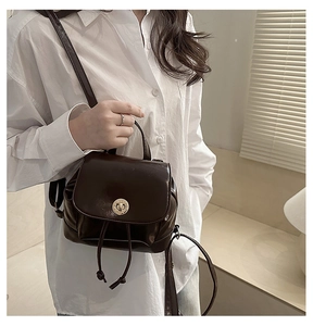 Detail of a dark brown glossy leather backpack with gold turn-lock and drawstring closure