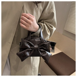 Détail du sac seau en cuir marron foncé avec nœud et clous métalliques en étoile