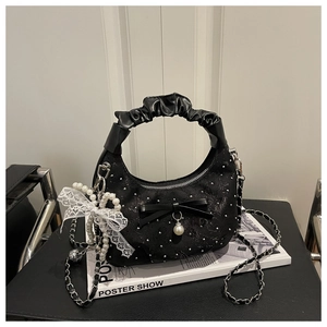 Detail of black pleated handbag with lace bow, pearl pendant and shimmering sequins