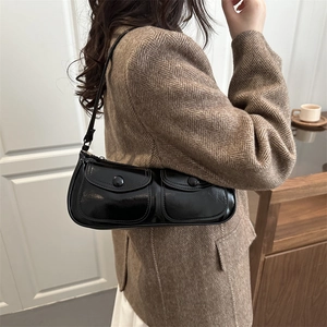 Sac sous le bras noir brillant à deux poches porté à l'épaule par un mannequin