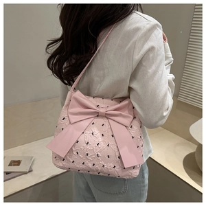 Detailed view of pink pleated tote bag with large bow decoration on model's shoulder