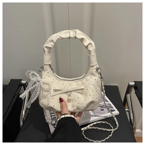 Detail of ruched handle, jacquard fabric with crystals and pearl bow on a beige hobo bag