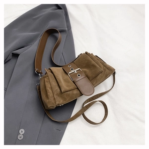 Détail d'un sac bandoulière marron avec boucle oversize sur fond de manteau gris