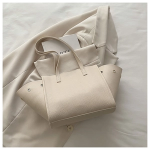 Détails du grain de cuir litchi et des œillets en métal du sac cabas crème