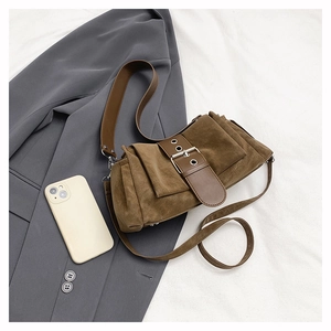 Détail du sac bandoulière en daim marron avec grande boucle et large bandoulière
