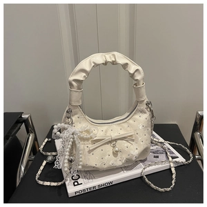 Close-up of cream pleated handbag with lace overlay, sparkling rhinestones and pearl bow charms