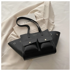 Détail du sac cabas noir à texture litchi avec doubles poches sur un blazer beige