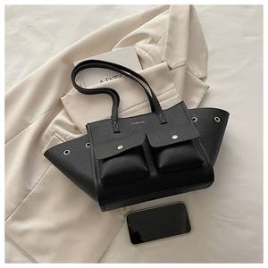 Détail d'un sac cabas en cuir noir avec poches cargo et finitions métalliques dorées