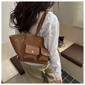 Dettaglio borsa a secchiello in pelle martellata marrone con tasche frontali e chiusura dorata