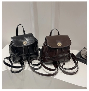 Detail of mini leather backpacks in black and brown with glossy finish and gold metal hardware