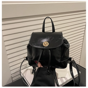 Detail of black glossy leather mini backpack with gold twist lock and drawstring