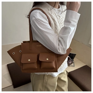 Détail du cabas en cuir grainé marron avec poches frontales et lettrage doré