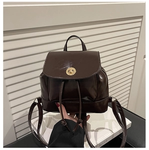 Macro detail of dark brown faux leather backpack with gold clasp and smooth texture