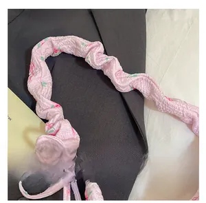 Dettaglio della tracolla rosa a fiori con pieghe su sfondo di un blazer nero