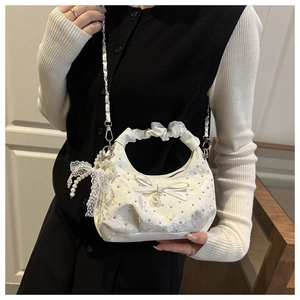 Detail of white lace handbag featuring rhinestone accents and pearl chain strap