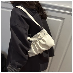 Détail du sac plissé en cuir blanc avec nœud et étoile argentée sur fond crème élégant