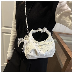 Close-up of white crescent lace bag with sparkling rhinestones and pearl bow charms