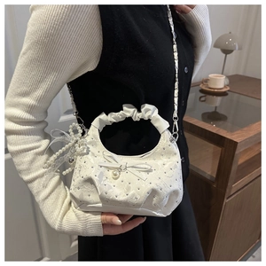 Detail of white pleated handbag with pearl butterfly ornament and elegant lace charm