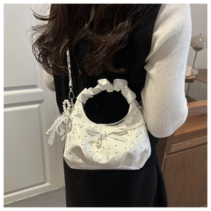 Detail of white rhinestones handbag with bow pearl charm and ruffled handle