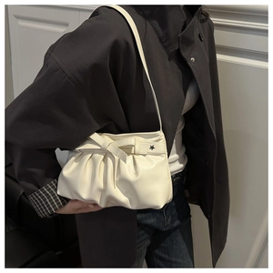 Détail du sac plissé blanc crème avec grand nœud et clous métalliques en étoile