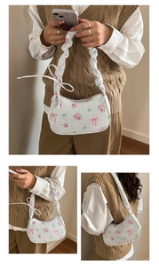 Dettaglio borsa sottobraccio bianca a fiori con tracolla a pieghe e fiocco rosa