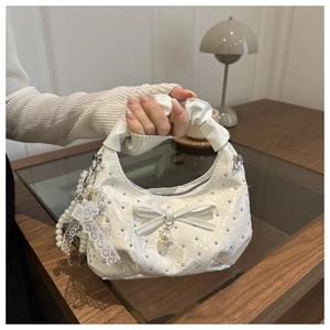 Detail of white bow bag with floral jacquard fabric, pearls, and sparkling rhinestones