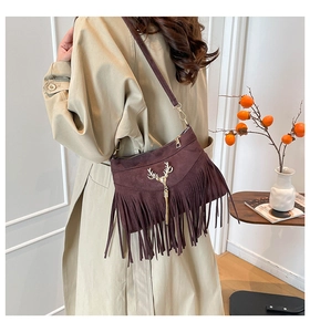 Détail du sac à franges vintage avec décoration tête de cerf dorée sur tissu en daim