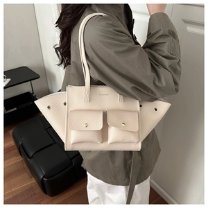 Dettaglio della borsa tote beige con grana litchi e tasche frontali con bottoni in metallo