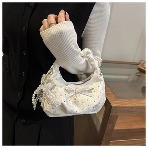 Close-up of white lace hobo bag with delicate bow and pearl pendant details