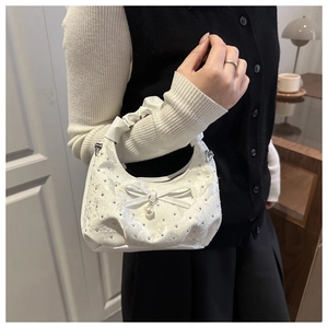 Close-up of white ruffled crescent bag featuring shimmering rhinestones and a pearl bow