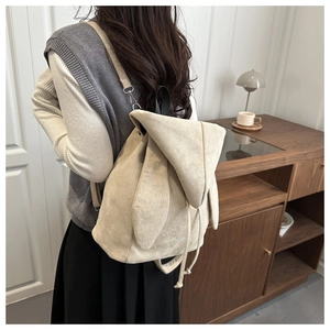 Dettaglio dello zaino beige con orecchie da coniglio in morbido camoscio su modella