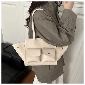 Détail du sac fourre-tout en cuir crème avec ailes latérales et poches à boutons