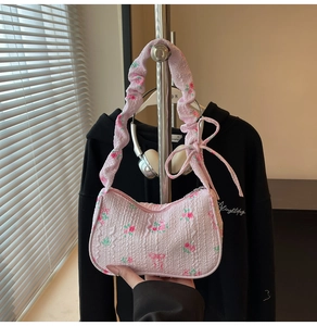 Detail of pink floral underarm bag with ruffled texture and ribbon bow decoration