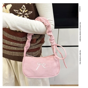Detailed texture of pink corduroy shoulder bag with elegant white bow embroidery