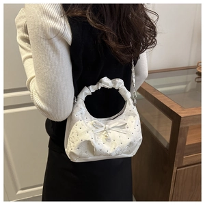 Detail of white lace handbag with rhinestone accents, pearl bow, and ruched handle design