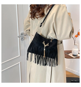 Détail du sac bandoulière à franges noires avec tête de cerf dorée sur trench beige