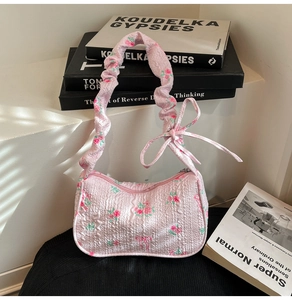 Close-up of pink quilted floral handbag featuring rose patterns and a bow detail