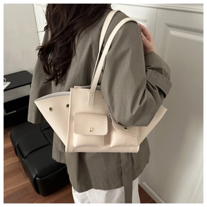 Sac bandoulière en cuir beige avec design à ailes porté par un mannequin pour le travail