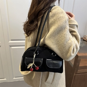 Retro black baguette bag with cherry charms worn as a shoulder bag in minimalist interior