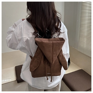 Dettaglio dello zaino in pelle scamosciata marrone con design unico a cappuccio