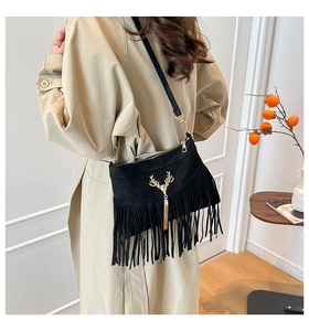 Détail du sac bandoulière noir à franges avec tête de cerf dorée et longs glands