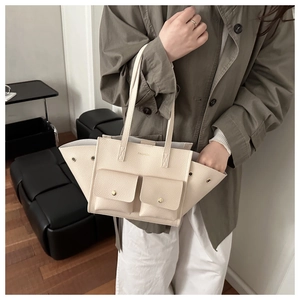 Dettaglio della borsa tote bianco crema in pelle martellata con tasche anteriori a patta