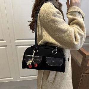 Minimalist black Boston shoulder bag with dual front pockets and a cherry charm