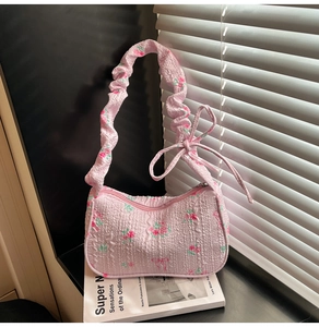 Detailed shot of pink floral bubble fabric underarm bag with ruffled strap and bow