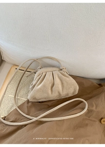 Detail of a beige suede ruched cloud bucket bag on a vintage aesthetic background