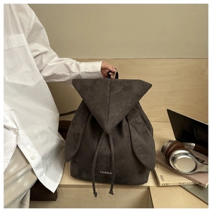 Zaino marrone in pelle scamosciata con tasche a orecchie di coniglio su scrivania e accessori