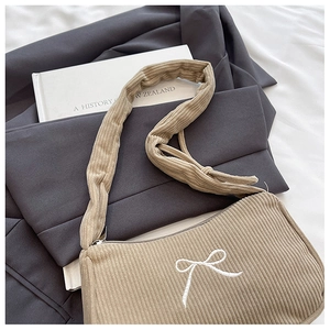 Detail of khaki corduroy texture and white bow embroidery on a casual shoulder bag
