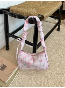 Detailed view of pink floral pattern underarm bag with ruffled strap and side bow decoration