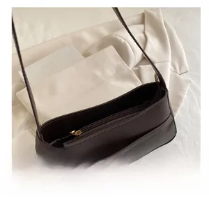 Detail view of smooth metal zipper and leather texture on a dark brown shoulder bag